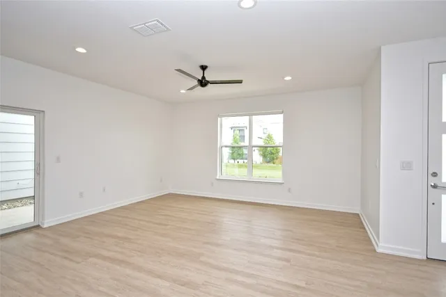 an empty room with windows and ceiling fan