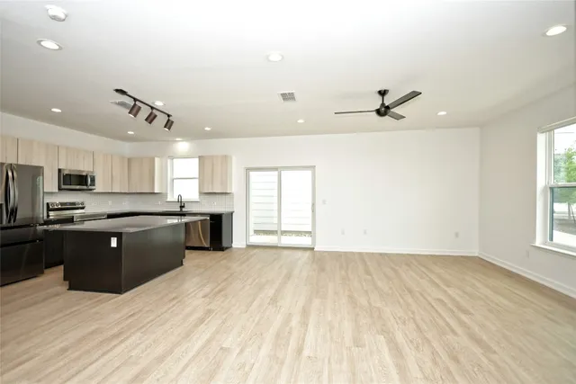 a large kitchen with cabinets wooden floor and stainless steel appliances