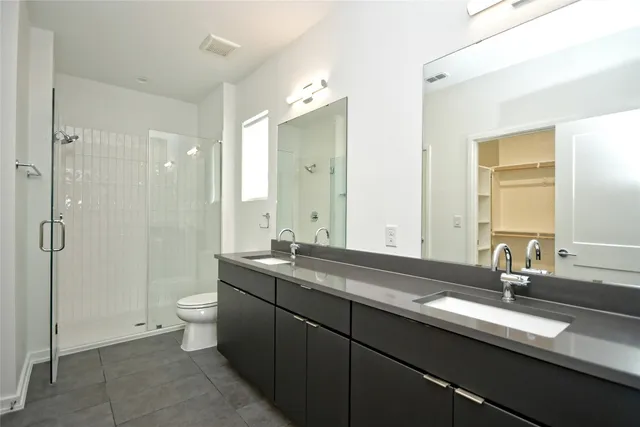 a bathroom with a double vanity sink toilet and shower