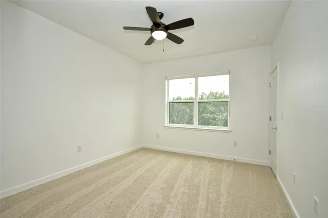 an empty room with a window and a fan