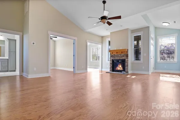 a view of a livingroom with wooden floor a ceiling fan and windows