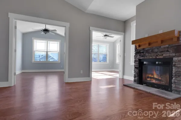 an empty room with wooden floor fire place and windows