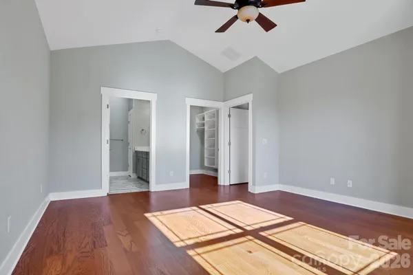 an empty room with wooden floor and ceiling fan