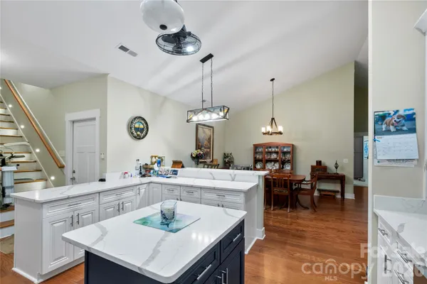a living room with stainless steel appliances furniture a dining table and a chandelier