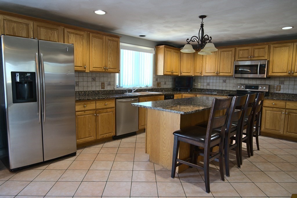 8 Sparrow Road Stoughton, MA 02072 - Photo 10 of 28 a kitchen with stainless steel appliances a sink a stove a table and chairs