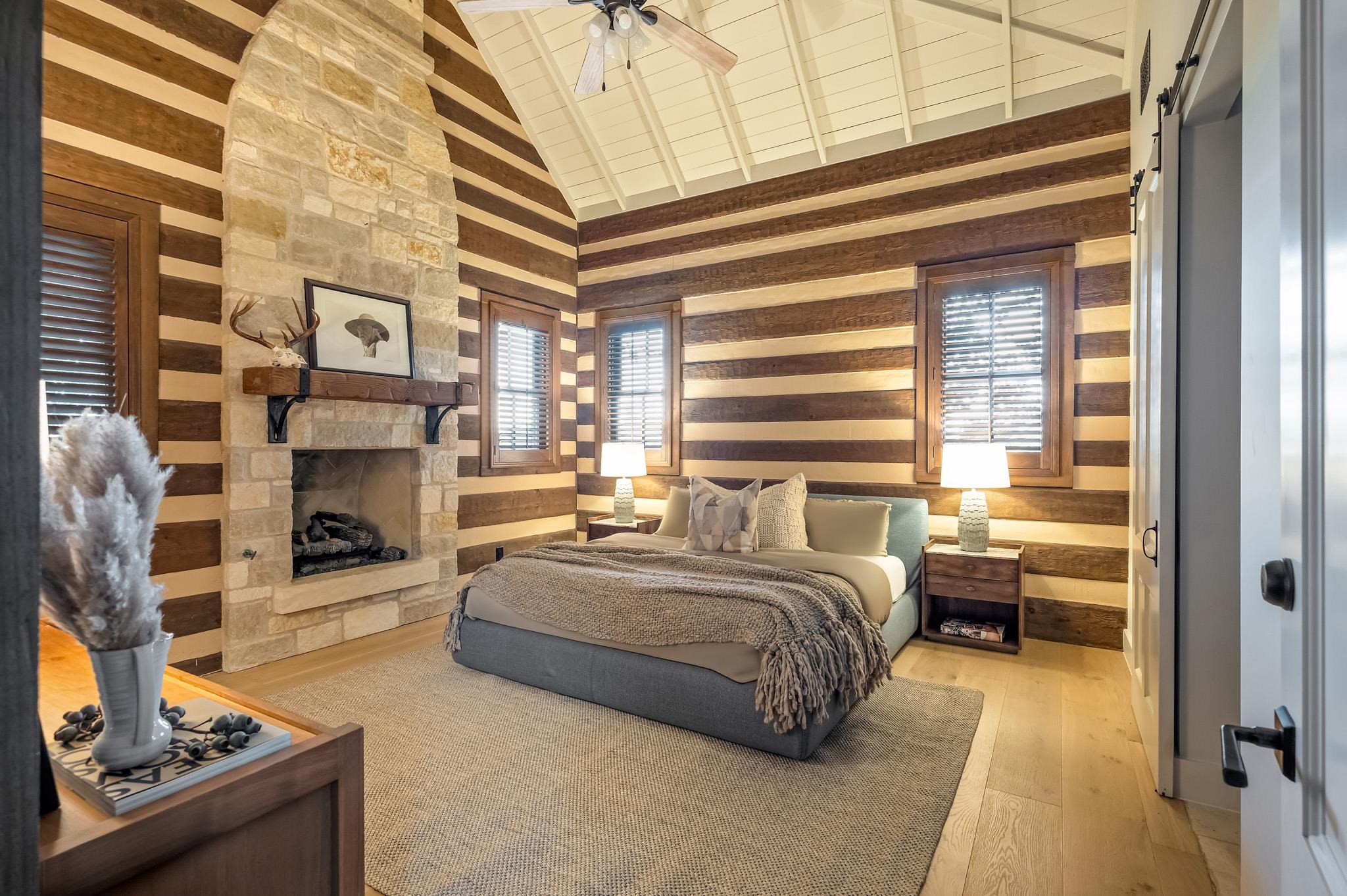 65 Riviera Cove Fredericksburg, TX 78624 - Photo 10 of 26 a spacious bedroom with a balcony a bed and a fireplace