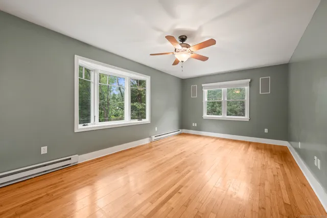 a view of an empty room with a window and wooden floor