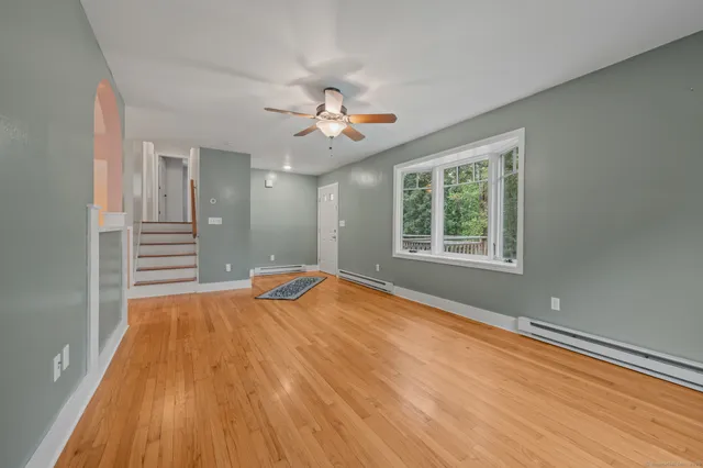 a view of an empty room with wooden floor and a window