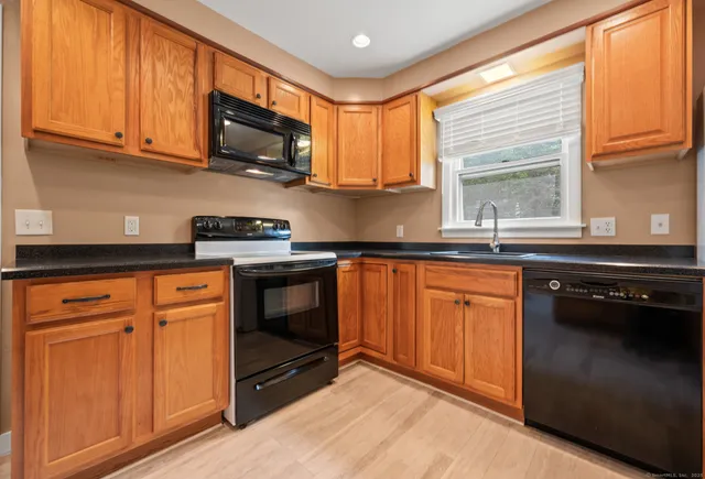 a kitchen with granite countertop wooden cabinets stainless steel appliances and a window