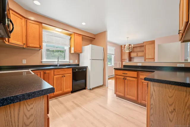 a kitchen with stainless steel appliances granite countertop a refrigerator a sink dishwasher and wooden cabinets with wooden floor