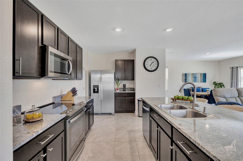 5758 Hollingworth Trail Wesley Chapel, FL 33545 - Photo 4 of 33 a open kitchen with stainless steel appliances granite countertop a sink a stove oven and granite countertops