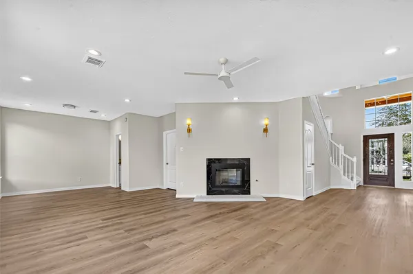 a view of a livingroom with a fireplace a ceiling fan and wooden floor