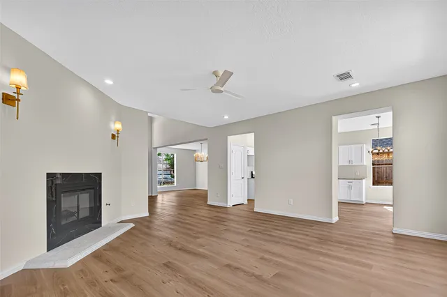 a view of an empty room with wooden floor and a fireplace