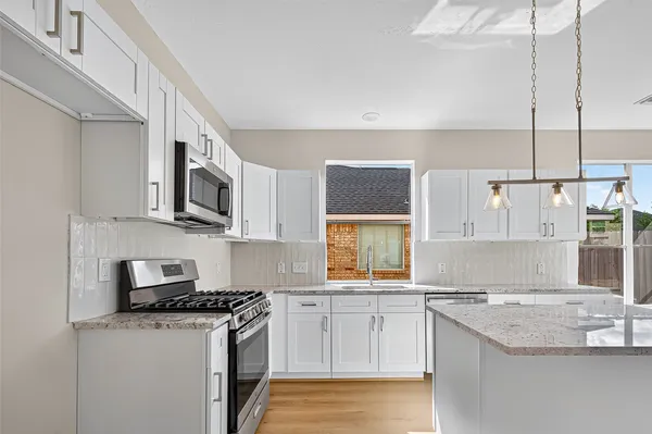 a kitchen with stainless steel appliances granite countertop a sink stove and microwave