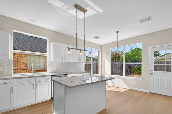 a kitchen with granite countertop a stove a sink a center island and windows