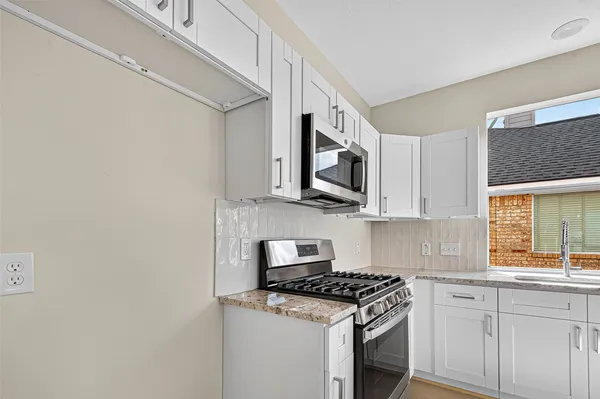 a kitchen with stainless steel appliances white cabinets and a stove top oven