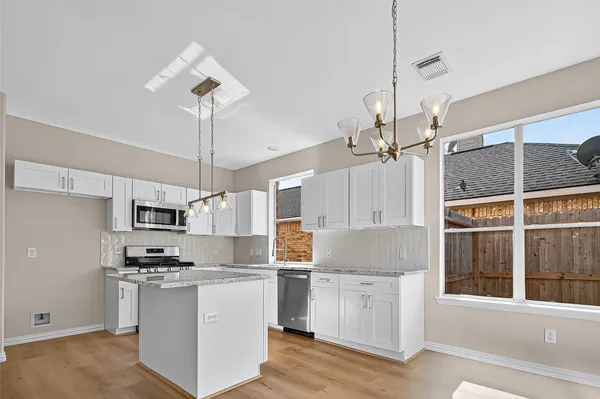 a kitchen with kitchen island granite countertop a sink cabinets and stainless steel appliances