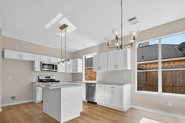 a kitchen with kitchen island granite countertop a sink cabinets and stainless steel appliances