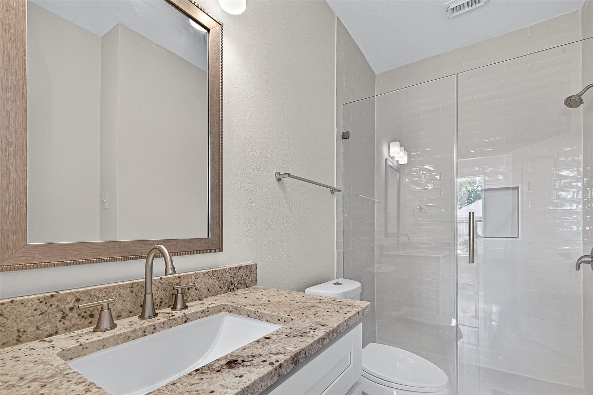 21310 Timber Pines Drive Spring, TX 77388 - Photo 32 of 49 a bathroom with a granite countertop sink toilet a shower and a mirror