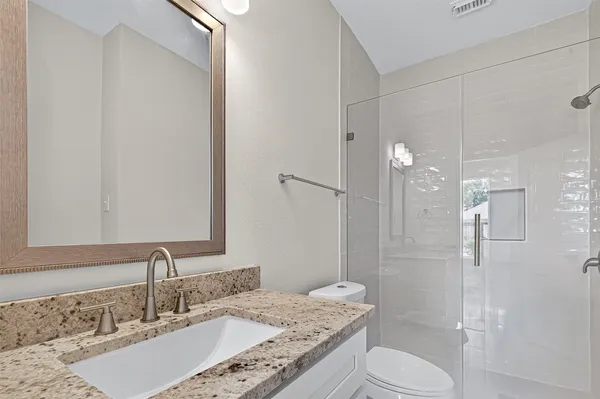 a bathroom with a granite countertop sink toilet a shower and a mirror