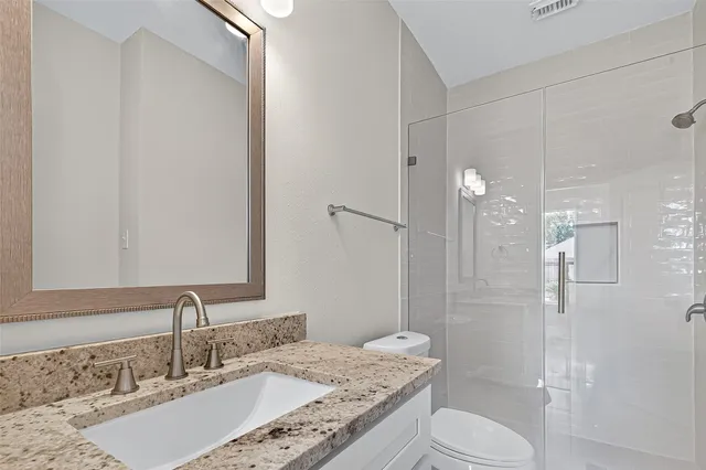 a bathroom with a granite countertop sink toilet a shower and a mirror