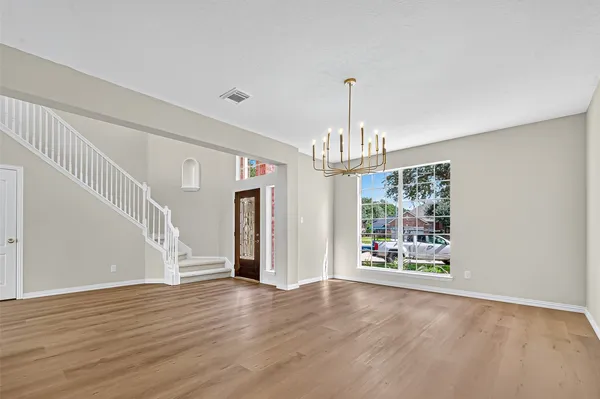 a view of a room with wooden floor chandelier and windows