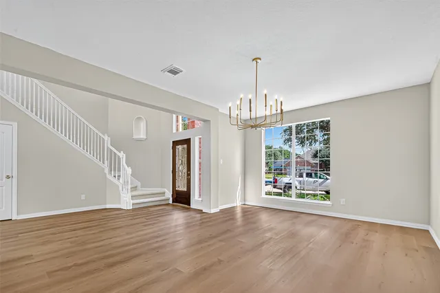 a view of a room with wooden floor chandelier and windows