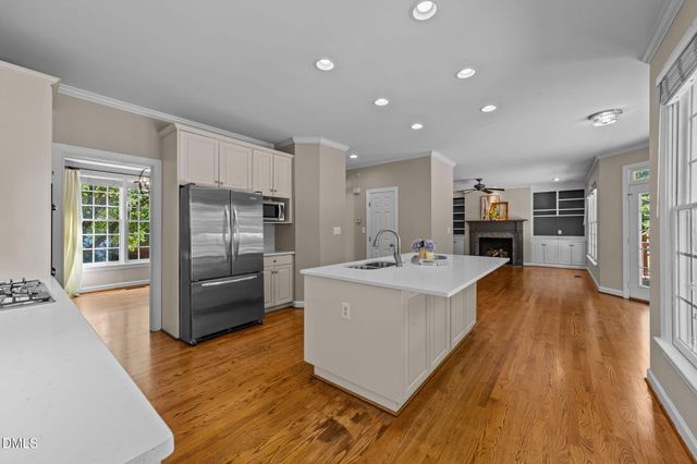 a large white kitchen with wooden floor and a refrigerator