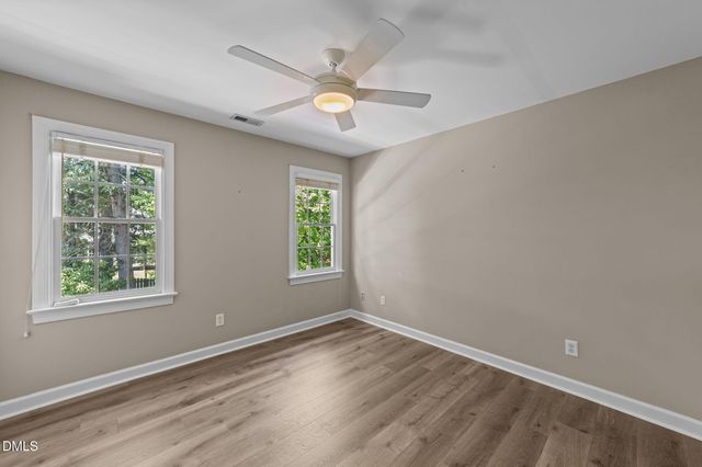 an empty room with wooden floor fan and windows