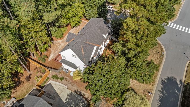 an aerial view of a house with a yard and covered with trees