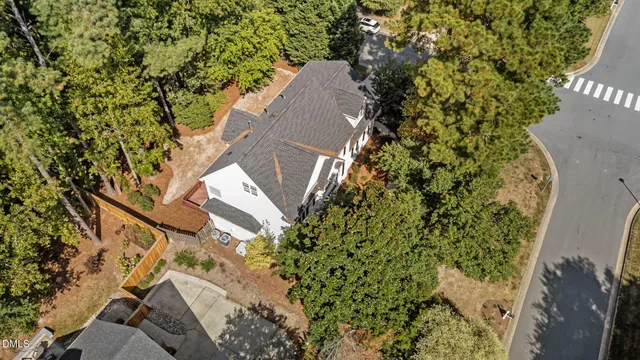 an aerial view of a house with a yard and covered with trees