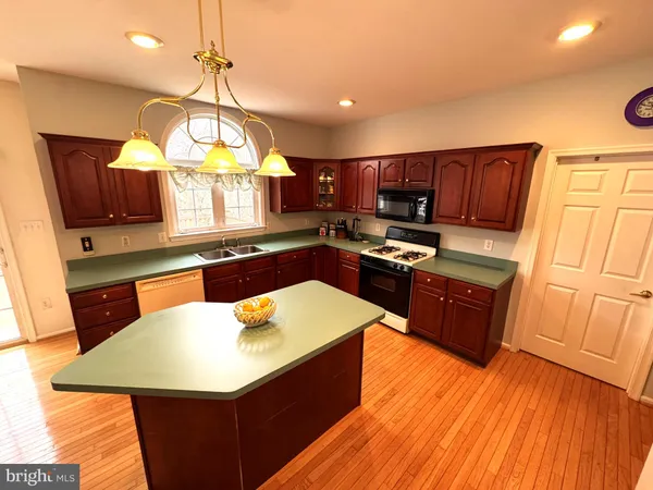 a kitchen with stainless steel appliances kitchen island granite countertop wooden cabinets a stove a sink and a microwave