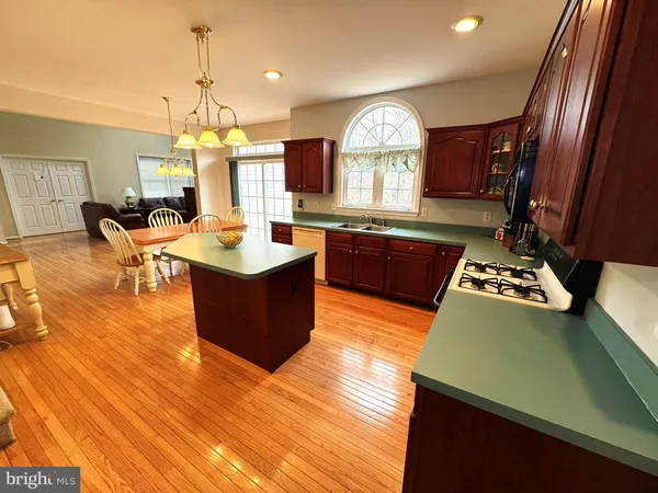 a kitchen with stainless steel appliances granite countertop a sink a stove and a wooden floors