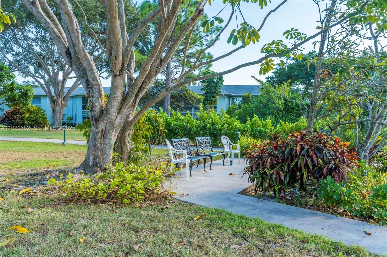 2300 Southwest 22nd Avenue, Unit 109 Delray Beach, FL 33445 - Photo 34 of 49 a view of a backyard with table and chairs and a large tree
