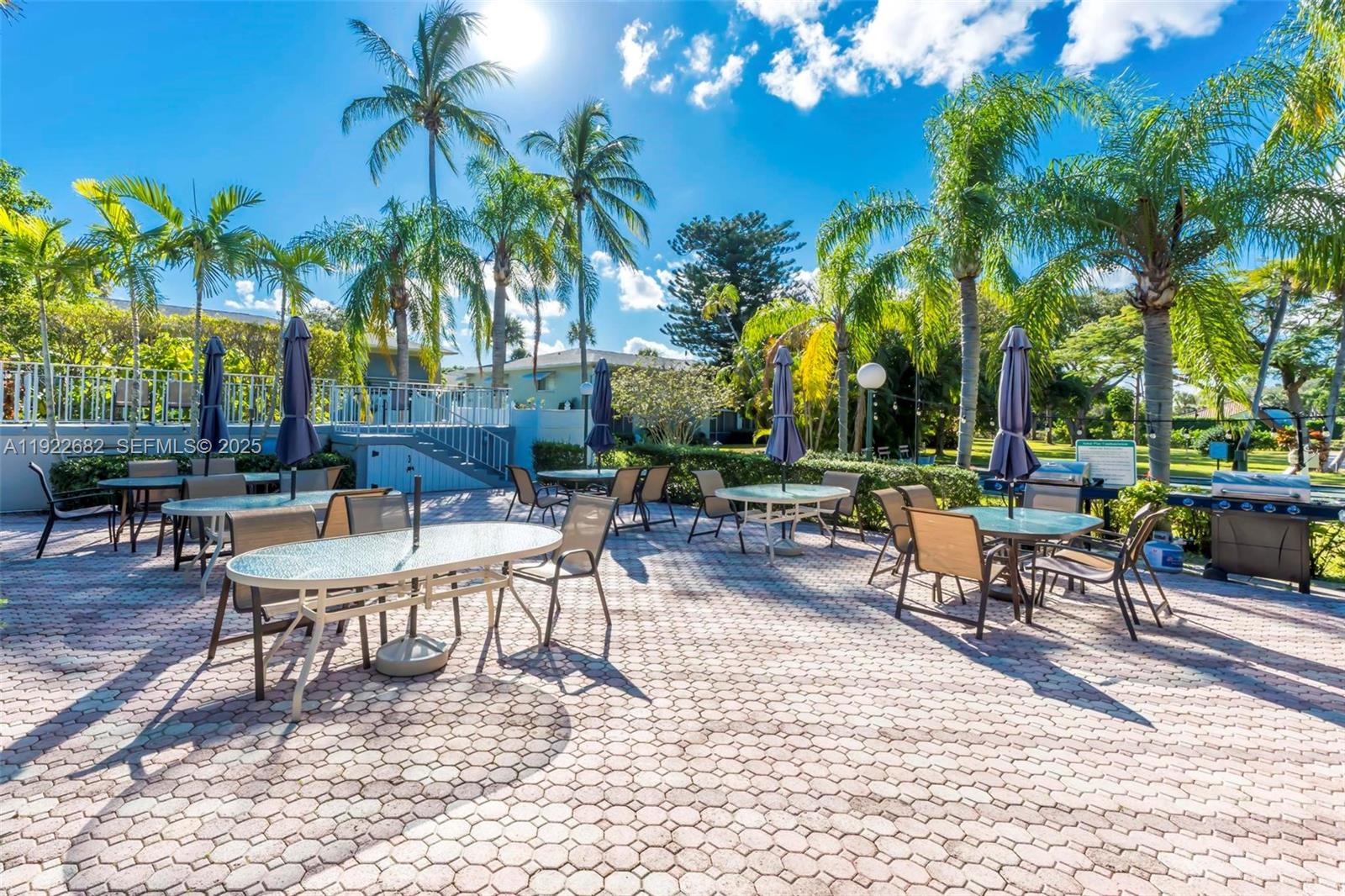 2300 Southwest 22nd Avenue, Unit 109 Delray Beach, FL 33445 - Photo 37 of 49 a view of a patio with a table and chairs under palm trees