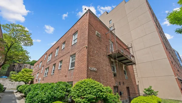 a view of a brick house with a large window and potted plants