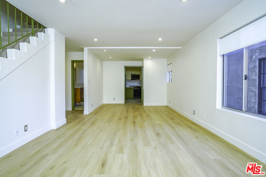 a view of empty room with wooden floor and entryway