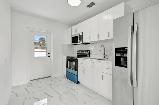 a kitchen with stainless steel appliances a refrigerator and white cabinets