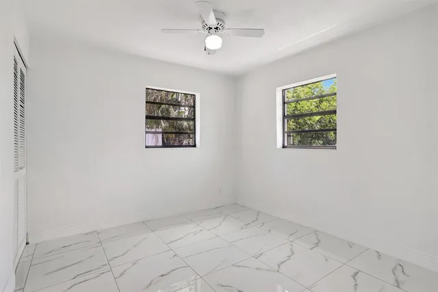 an empty room with windows and fan