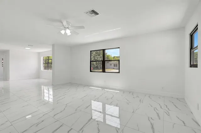 an empty room with windows and fan