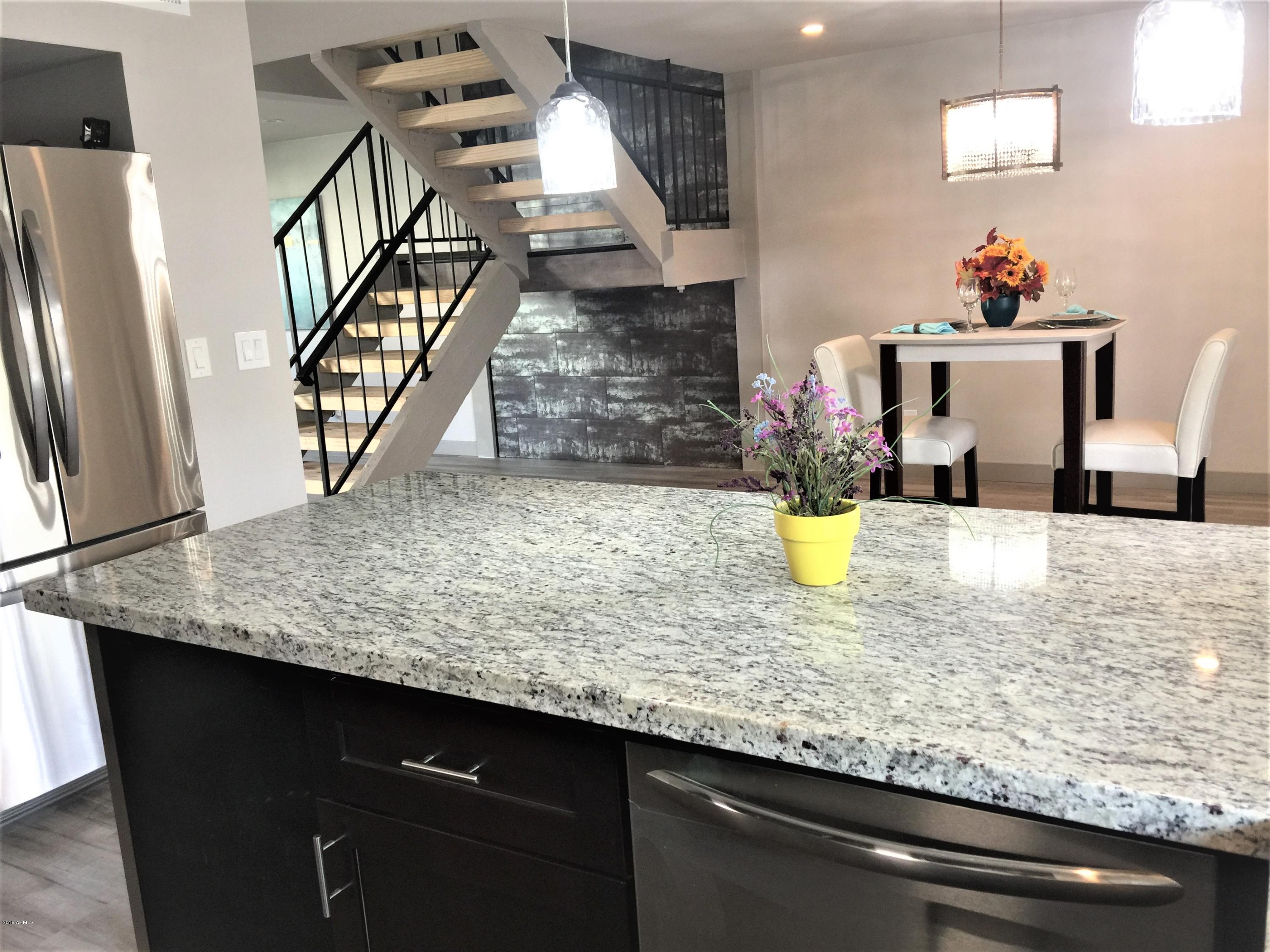 4221 North Miller Road Scottsdale, AZ 85251 - Photo 2 of 20 a kitchen with kitchen island a counter top space a sink wooden floor and a refrigerator