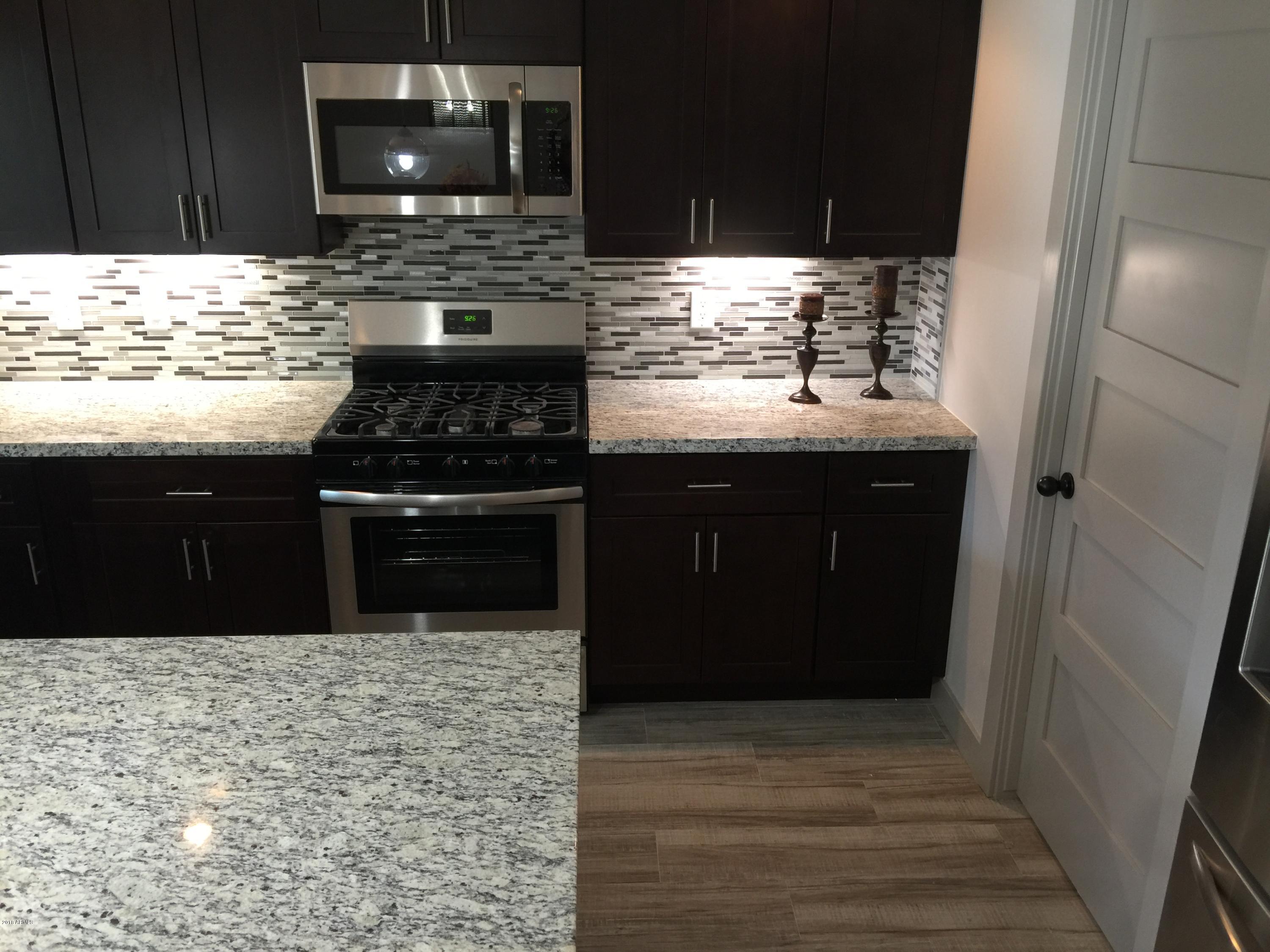 4221 North Miller Road Scottsdale, AZ 85251 - Photo 7 of 20 a kitchen with a sink and a stove with wooden cabinets