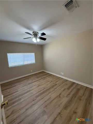 a view of an empty room with wooden floor and a window