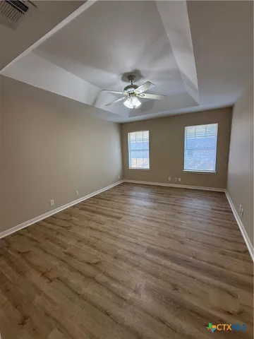 a view of an empty room with window and wooden floor