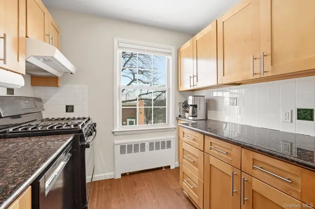 a kitchen with stainless steel appliances granite countertop a sink a stove and a wooden floors