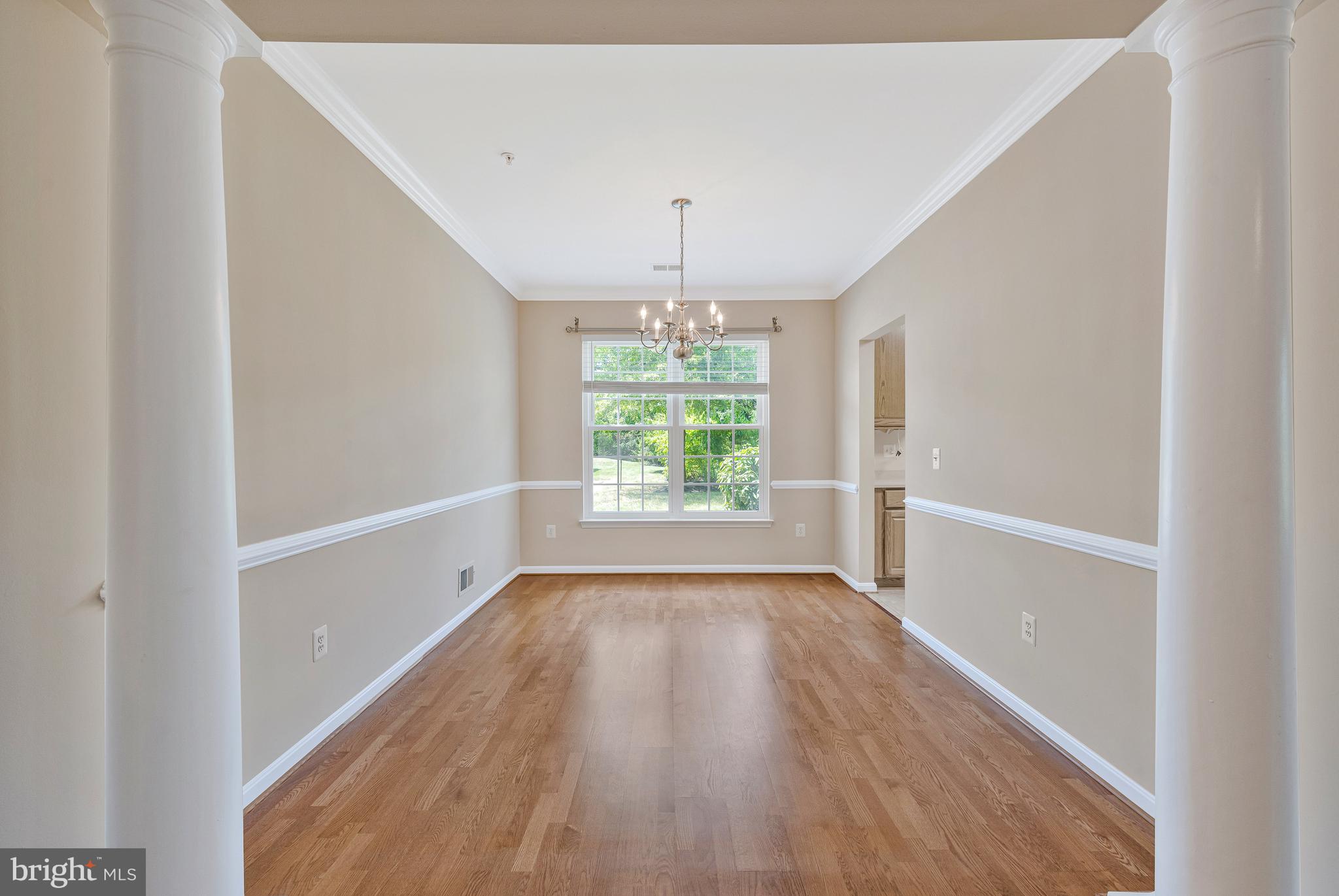8600 Roaming Ridge Way, Unit 106 Odenton, MD 21113 - Photo 11 of 52 an empty room with wooden floor chandelier and windows