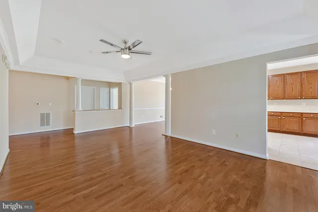 an empty room with wooden floor chandelier and windows