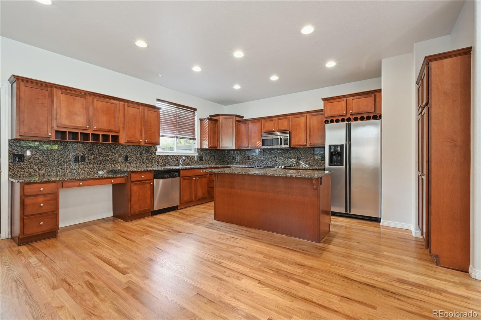 3515 Perry Street Denver, CO 80212 - Photo 11 of 40 a kitchen with stainless steel appliances granite countertop a refrigerator a sink dishwasher a stove with large countertops and wooden floor