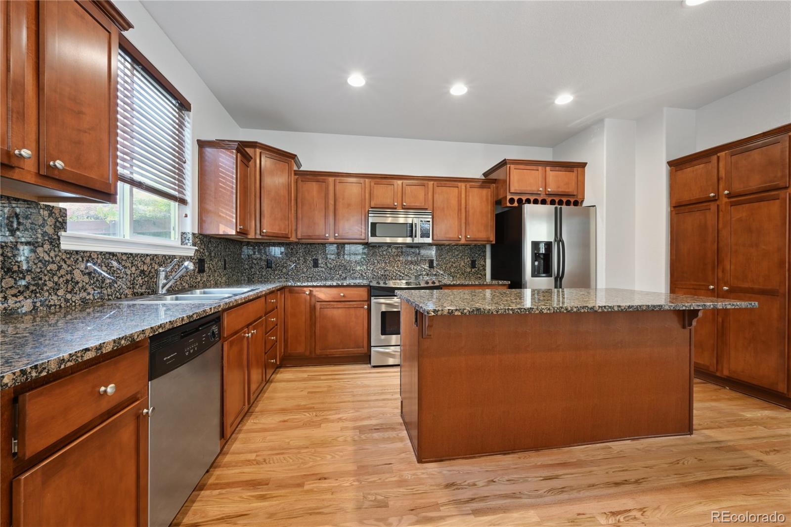 3515 Perry Street Denver, CO 80212 - Photo 13 of 40 a large kitchen with stainless steel appliances granite countertop a stove a sink dishwasher and a microwave oven with large wooden cabinets