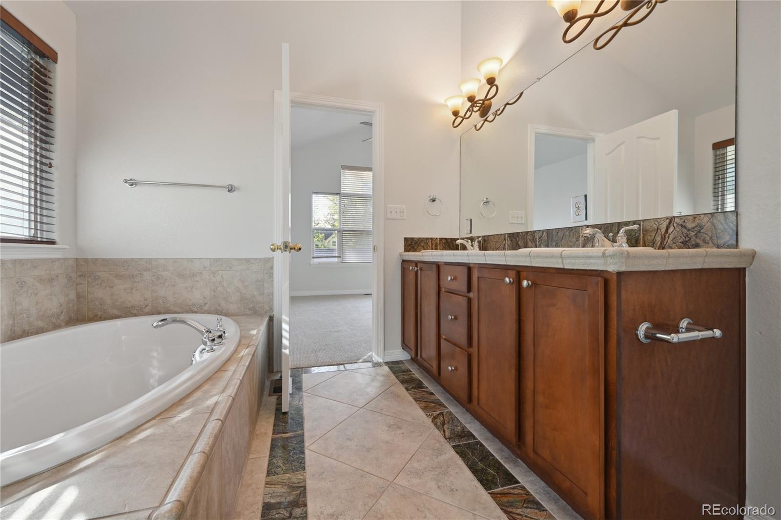 3515 Perry Street Denver, CO 80212 - Photo 18 of 40 a spacious bathroom with a granite countertop sink a mirror a bathtub and shower